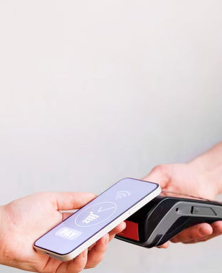 Two hands holding a smartphone and a card reader against a light gray background